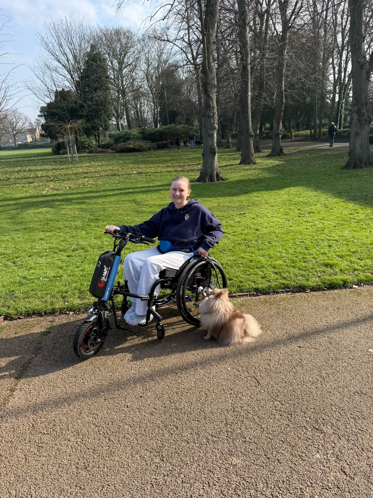 Dee, a wheelchair-using dog trainer in Middlesbrough, at the park with a Pomeranian