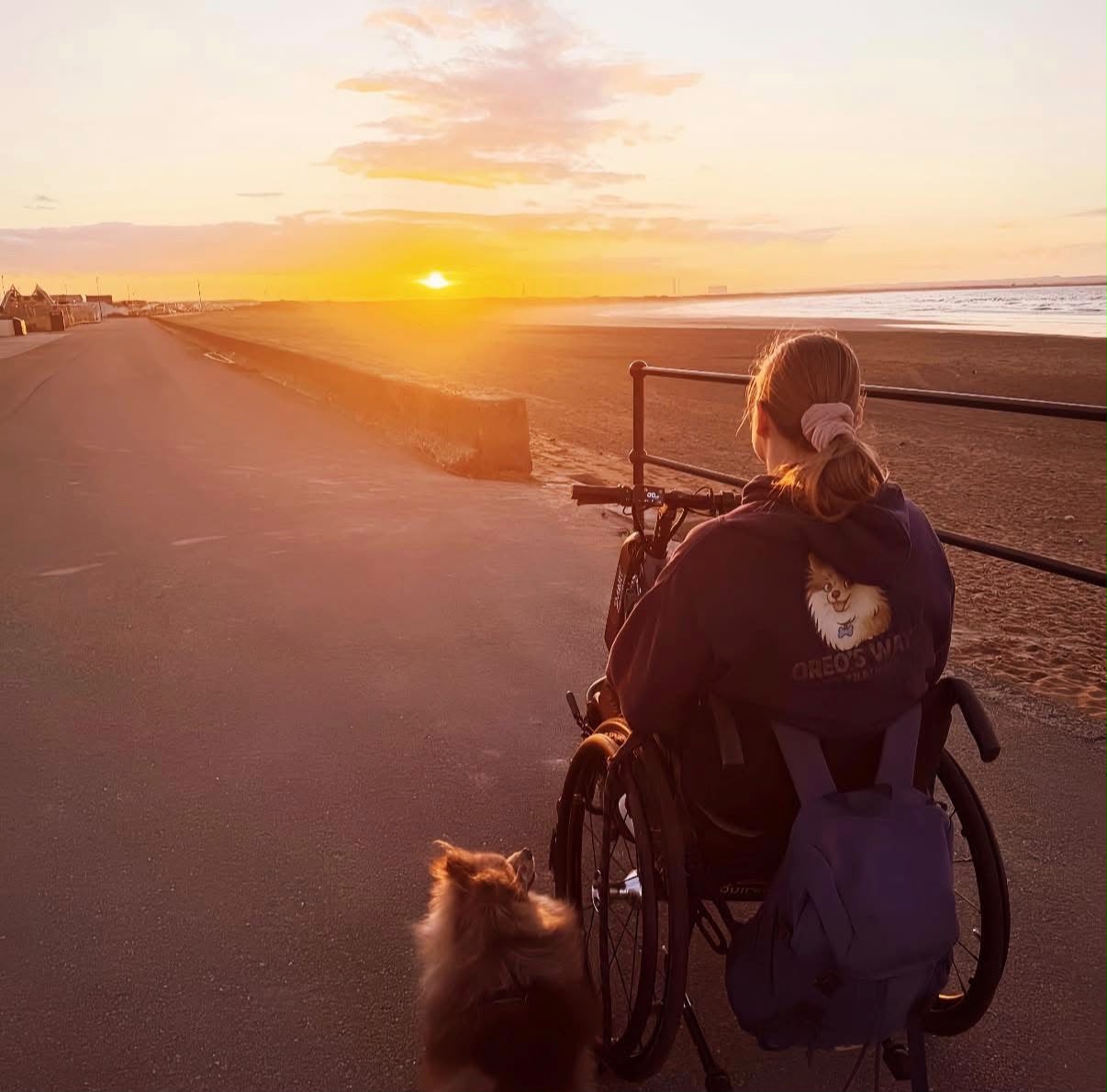 Dee and her assistance dog Oreo on the seafront promenade at sunset